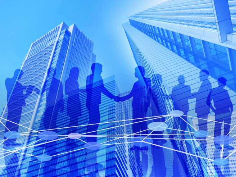 高層ビルあおり背景に握手などビジネスマン集団のシルエット